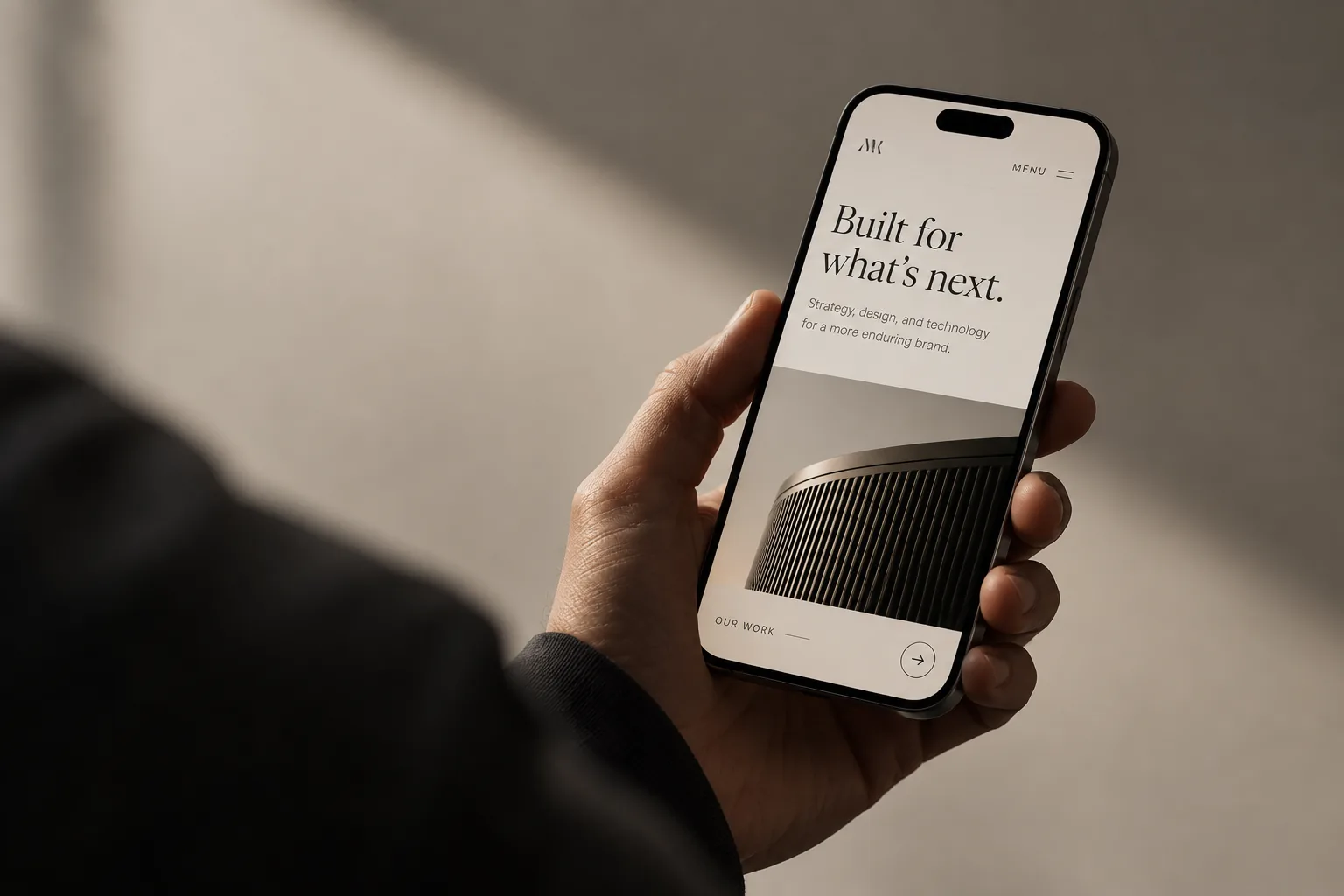 Hand holding a phone displaying a custom-built website homepage